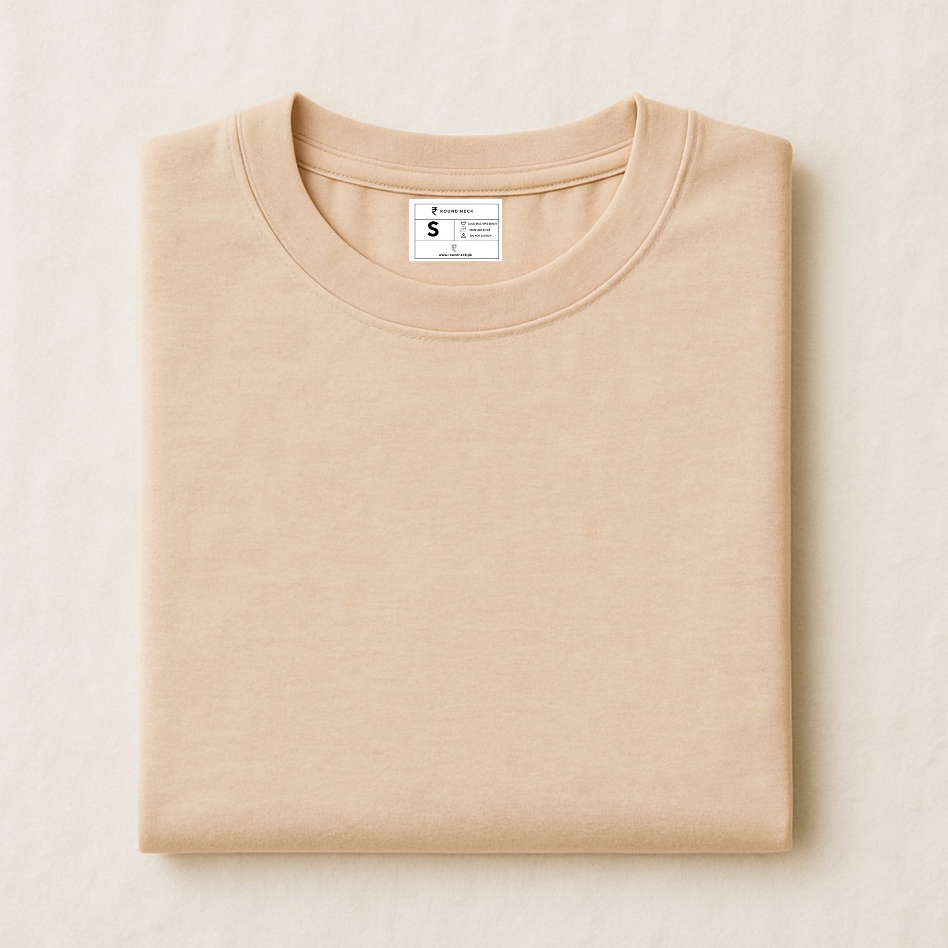 Folded beige sweatshirt with a label on a light beige background