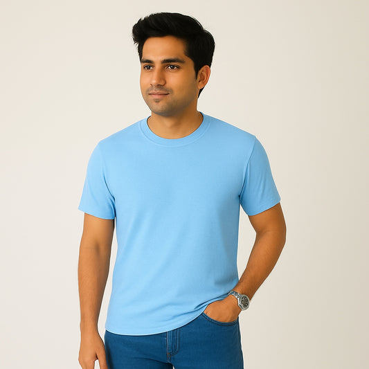 Man wearing a light blue t-shirt and dark blue jeans against a plain background